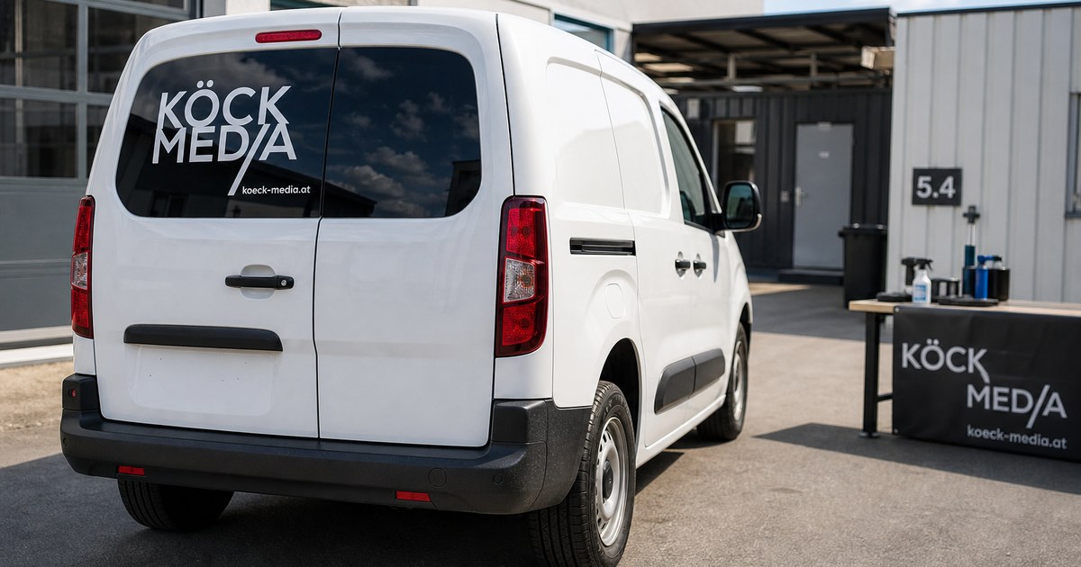 Heckscheibe eines Kleintransporters mit Schriftzug, leicht seitlich bei Tageslicht fotografiert